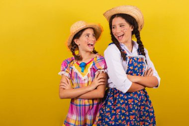 Festa Junina için tipik kıyafetler giyiyorlar. Kollar çapraz, mutlu bir şekilde gülümsüyor. Arraia partisi için.
