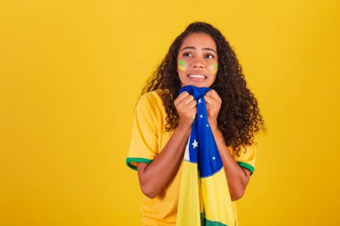 Genç siyah Brezilyalı kadın, futbol fanatiği. Brezilya bayrağıyla. Endişeli.