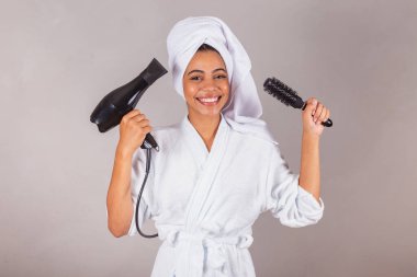 Güzel Brezilyalı siyah kadın, bornoz ve havlu giyiyor. Saç kurutma makinesi, fırça, güzellik salonu, spa, estetik konsepti..