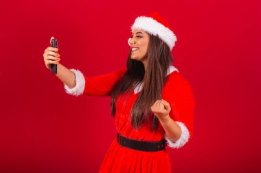 Noel kıyafetleri giymiş güzel Brezilyalı kadın, Noel Baba. Akıllı telefon kutlaması..