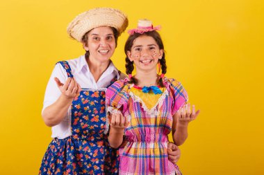 Büyükanne ve torun tipik Festa Junina kıyafetleri giymişler. Ellerinle çağır, davet et, buraya gel..