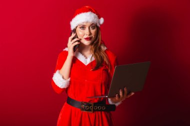 Güzel Brezilyalı kızıl saçlı kadın, Noel kıyafetleri giymiş, Noel Baba. Not defteri ve akıllı telefon tutuluyor, meşgul.