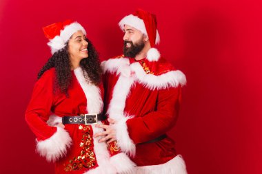 Brezilyalı çift, Noel için giyinmişler, Noel Baba, mumya Noel Baba. Siyah kadın ve beyaz adam. Birbirlerine bakıyorlar..