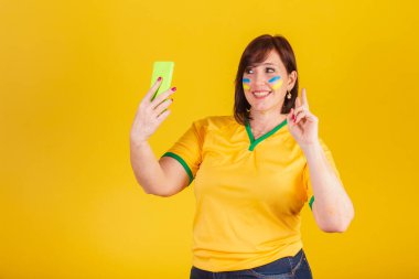 Kızıl saçlı kadın, Brezilyalı futbol fanatiği. Cep telefonuyla, akıllı telefonla yapılan video görüşmesi..