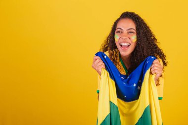 Genç siyah Brezilyalı kadın, futbol fanatiği. Brezilya bayrağıyla. bağıran hedef