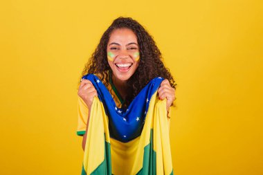 Genç siyah Brezilyalı kadın, futbol fanatiği. Brezilya bayrağıyla. bağıran hedef