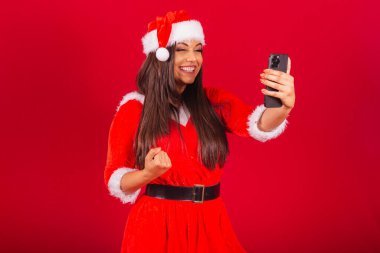 Noel kıyafetleri giymiş güzel Brezilyalı kadın, Noel Baba. Akıllı telefon kutlaması..