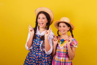 Festa Junina 'nın tipik kıyafetlerini giyiyorlar. Parmaklar çapraz, bükük, özlem dolu.