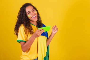 Genç siyah Brezilyalı, futbol taraftarı. oyun oynuyoruz, akıllı telefon.