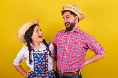 Baba ve kızı Festa Junina için tipik kıyafetler giyiyor. Elleri belinde. Arraia partisi için.