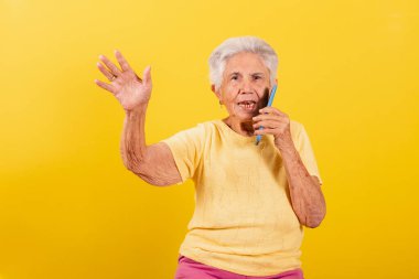Yaşlı kadın, cep telefonu, yaşlıların dijital ortama dahil edilmesi, çevrimiçi, akıllı telefon. Sesli arama ile konuşuyorum. Ve elini sallıyor..