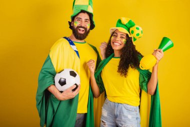 İki Brezilyalı futbol taraftarı, ulusun renginde giyinmiş, siyah kadın, beyaz erkek. bayrak ve aksesuarlar kullanarak