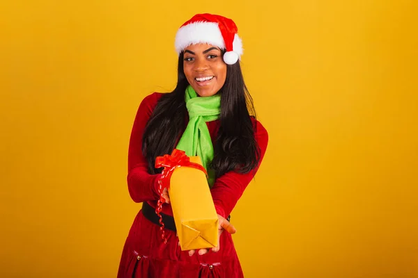 美しい黒ブラジルの女性 クリスマス服を着て サンタクロース 黄色の贈り物を渡します — ストック写真