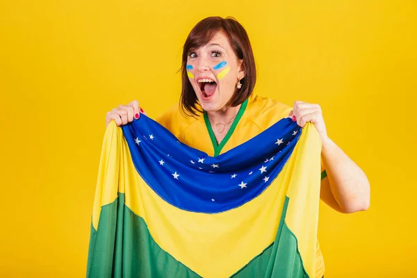 stock image red-haired woman, Brazilian soccer fan. fluttering with brazil flag, cheering and celebrating.