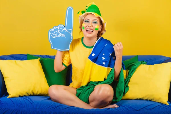 ブラジル人 泡の指のパーティーとソファの上にブラジルのサッカーファン — ストック写真