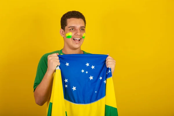 年轻的巴西男子足球迷 身穿绿色衣服 飘扬着巴西国旗 — 图库照片