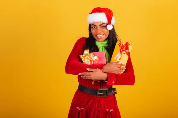 美しいブラジルの黒人女性は クリスマスの服を着て サンタクロース 2つの贈り物を抱きしめて — ストック写真