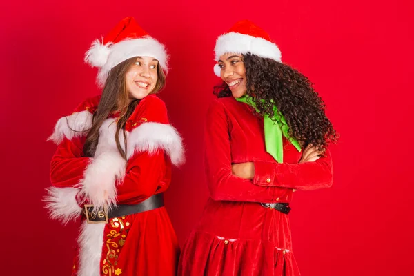 Två Frasilianska Kvinnliga Vänner Klädda Julkläder Tomteklor Armarna Korsade Optimistiskt — Stockfoto