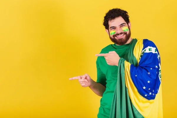 ブラジル出身のひげを生やした白人男性ブラジル出身のサッカーファン指で左を向け広告のための写真表示 — ストック写真