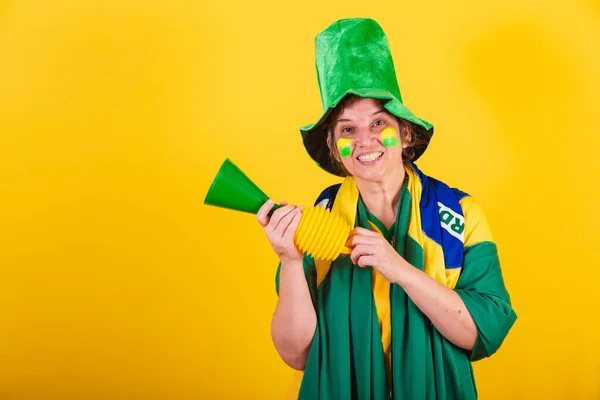 adult adult woman, soccer fan from brazil, wearing flag and hat, using horn noise, cheering.