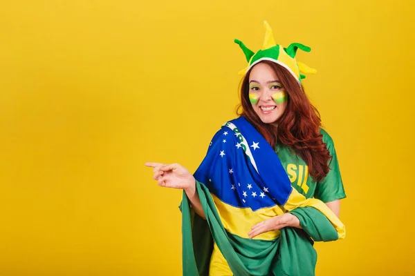 白种人 红头发的女人 来自巴西的足球迷 用手展示产品 — 图库照片