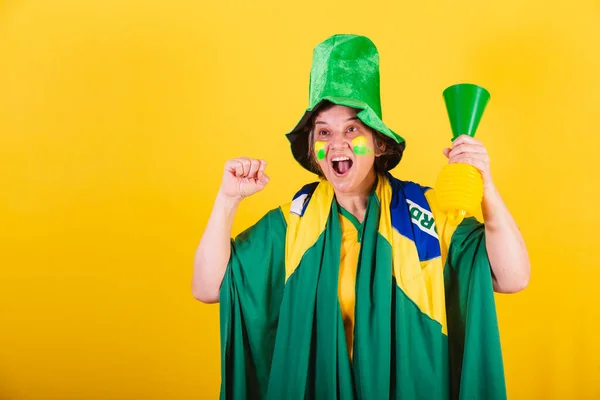 大人の女性ブラジルのサッカーファン旗と帽子をかぶってホーン ノイズを使って応援します — ストック写真