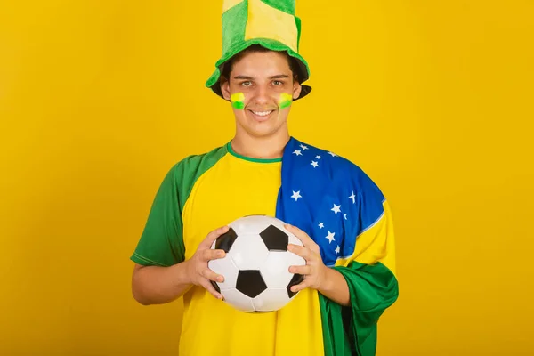 Młody Brazylijski Fan Piłki Nożnej Ubrany Zielono Trzymając Piłkę Brazylijską — Zdjęcie stockowe