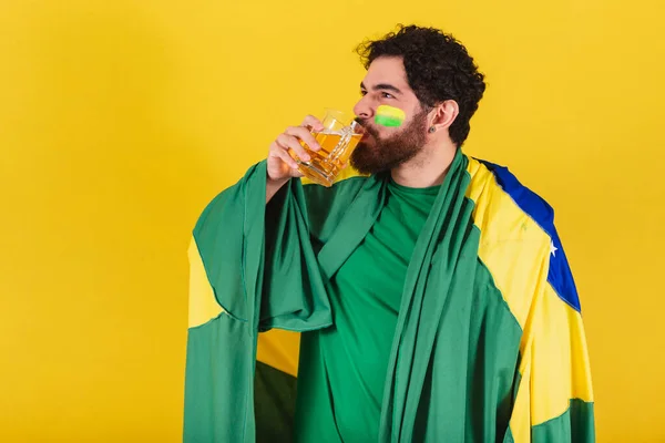 髭を生やした白人ブラジル人サッカーファンマグカップからビールを飲んでる 良いビールのコンセプト — ストック写真