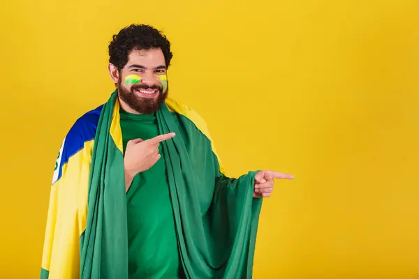 ブラジル出身の髭やブラジル人サッカーファンを持つ白人男性です指で右を指し広告写真表示 — ストック写真