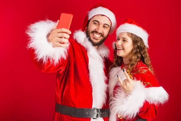 Brezilyalı Çift Noel Kıyafetleri Içinde Noel Baba Akıllı Telefon Kullanıyorlar — Stok fotoğraf