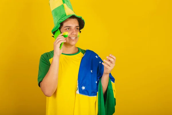 若いブラジル人のサッカーファン 緑の服を着てスマートフォンや携帯電話を使ってブラジルでオンラインで — ストック写真