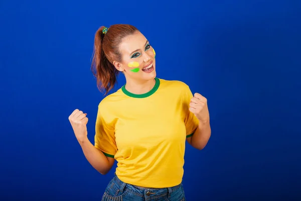 白人妇女 红头发 巴西球迷 巴西人 蓝色背景 庆祝和眨眼 — 图库照片