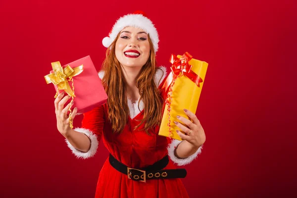 stock image beautiful Brazilian red-haired woman, dressed in Christmas clothes, Santa Claus. giving two presents to camera.