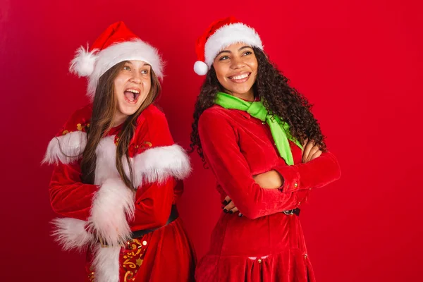 Två Frasilianska Kvinnliga Vänner Klädda Julkläder Tomteklor Armarna Korsade Optimistiskt — Stockfoto