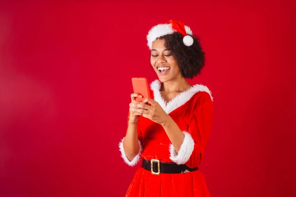 美しい黒系ブラジル人女性サンタ クラスママ クラスの格好をしてスマートフォンで何かを見ていました — ストック写真