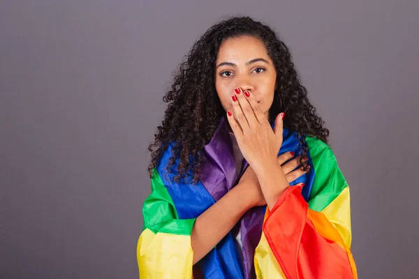 Young black Brazilian woman, covering her mouth, militancy with LGBT flag, diversity, fight against prejudice.