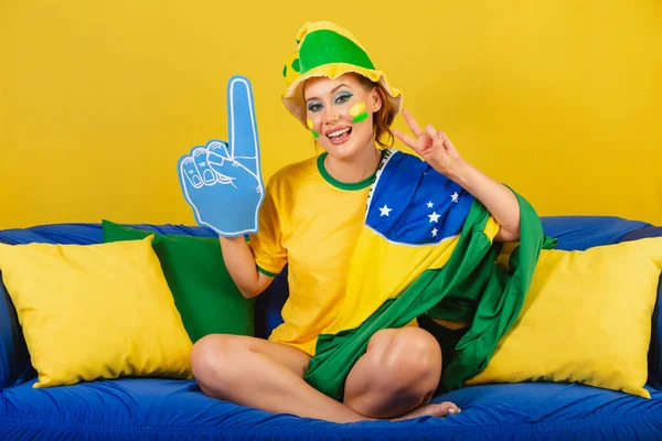 ブラジル人 泡の指のパーティーとソファの上にブラジルのサッカーファン — ストック写真