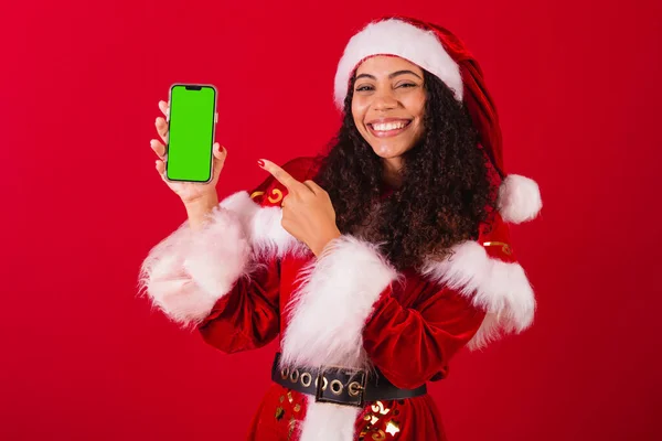 美丽的巴西黑人女人 穿着圣塔克洛斯的衣服 圣诞服装 手持手机 带有彩色屏幕 — 图库照片
