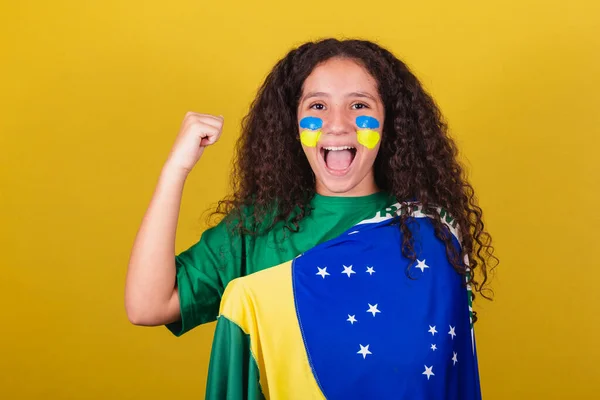 ブラジル人白人サッカーファンの女の子笑顔腕を上げ装飾された強さを示す — ストック写真