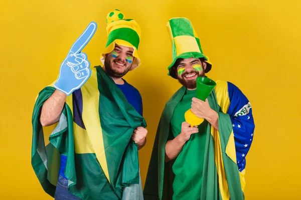 ブラジル人 ブラジル人 サッカーファンの2人の友人がブラジルの国旗 ホーン 指を使ってサッカーの試合で応援します — ストック写真