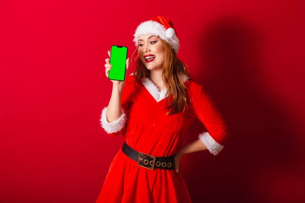 美丽的巴西红头发女人 穿着圣诞服装 圣诞老人 显示带有绿色彩色屏幕的智能手机 — 图库照片