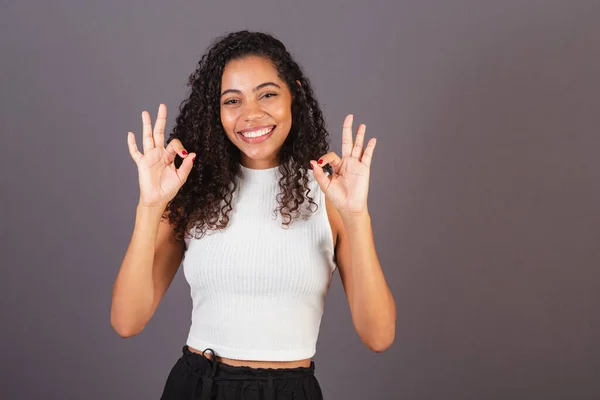 Young Brazilian black woman, ok sign with fingers.
