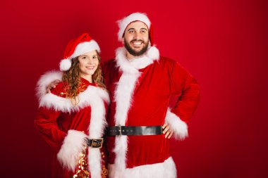 Brezilyalı çift, Noel kıyafetleri içinde, Noel Baba, kameraya gülümsüyor.