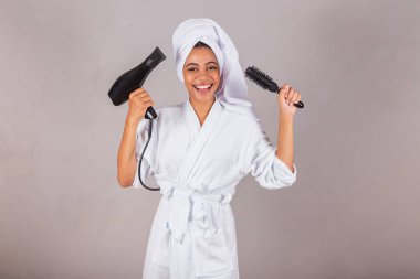 Güzel Brezilyalı siyah kadın, bornoz ve havlu giyiyor. Saç kurutma makinesi, fırça, güzellik salonu, spa, estetik konsepti..