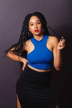 Güzel siyah Brezilyalı kadın, mavi giyinmiş. Yarı vücut portresi, gri sonsuzluk arkaplanı.