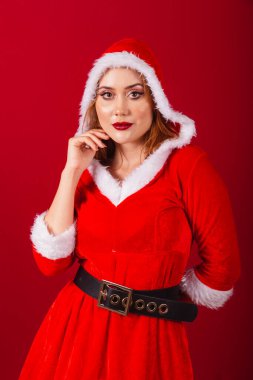 Güzel Brezilyalı kızıl saçlı kadın, Noel kıyafetleri giymiş, Noel Baba. şapka takıyor.