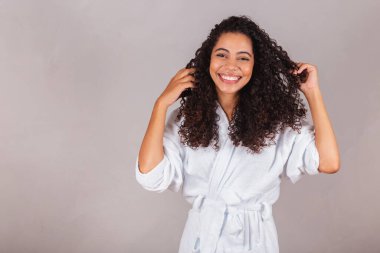 Bornoz ve havlu giymiş Brezilyalı siyahi kadın. Kıvırcık saç, spa, güzellik merkezi, saç bakımı. Saçlarını gösteriyor. bukleler.