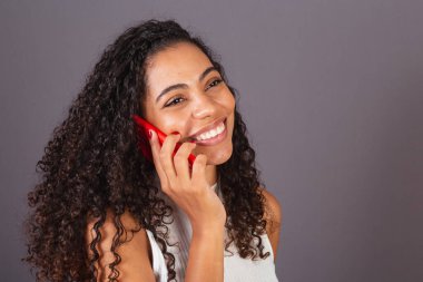 Genç Brezilyalı siyahi kadın kırmızı cep telefonuyla konuşuyor..