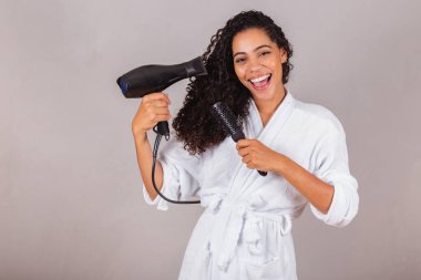 Güzel Brezilyalı siyah kadın, bornoz ve havlu giyiyor. Saç kurutma makinesi, fırça, spa, güzellik merkezi, saç bakımı..