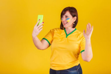 Kızıl saçlı kadın, Brezilyalı futbol fanatiği. Cep telefonuyla, akıllı telefonla yapılan video görüşmesi..